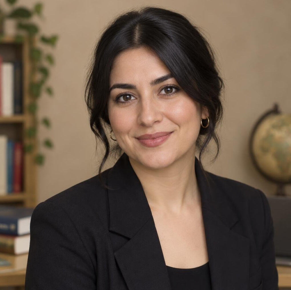 Portrait of a smiling woman of Turkish descent in a dark blazer